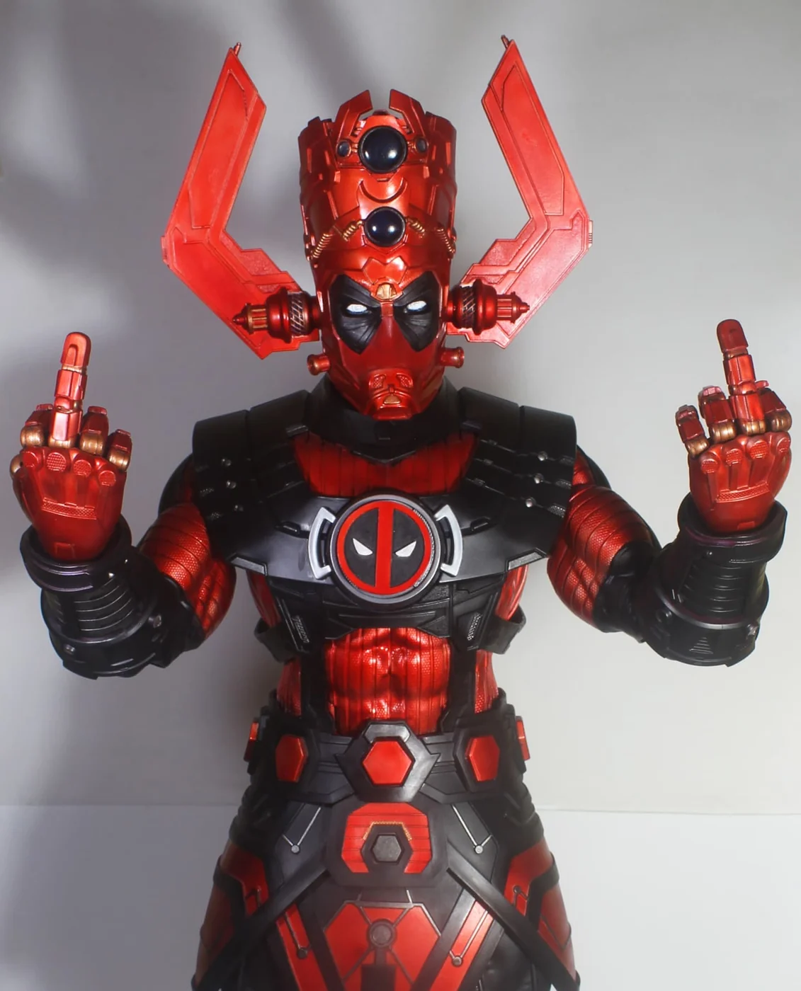 Close view of the Galactuspool custom, a Galactus scale figure in Deadpool red and black with the Deadpool mask and chest emblem, both hands raised with the middle fingers extended