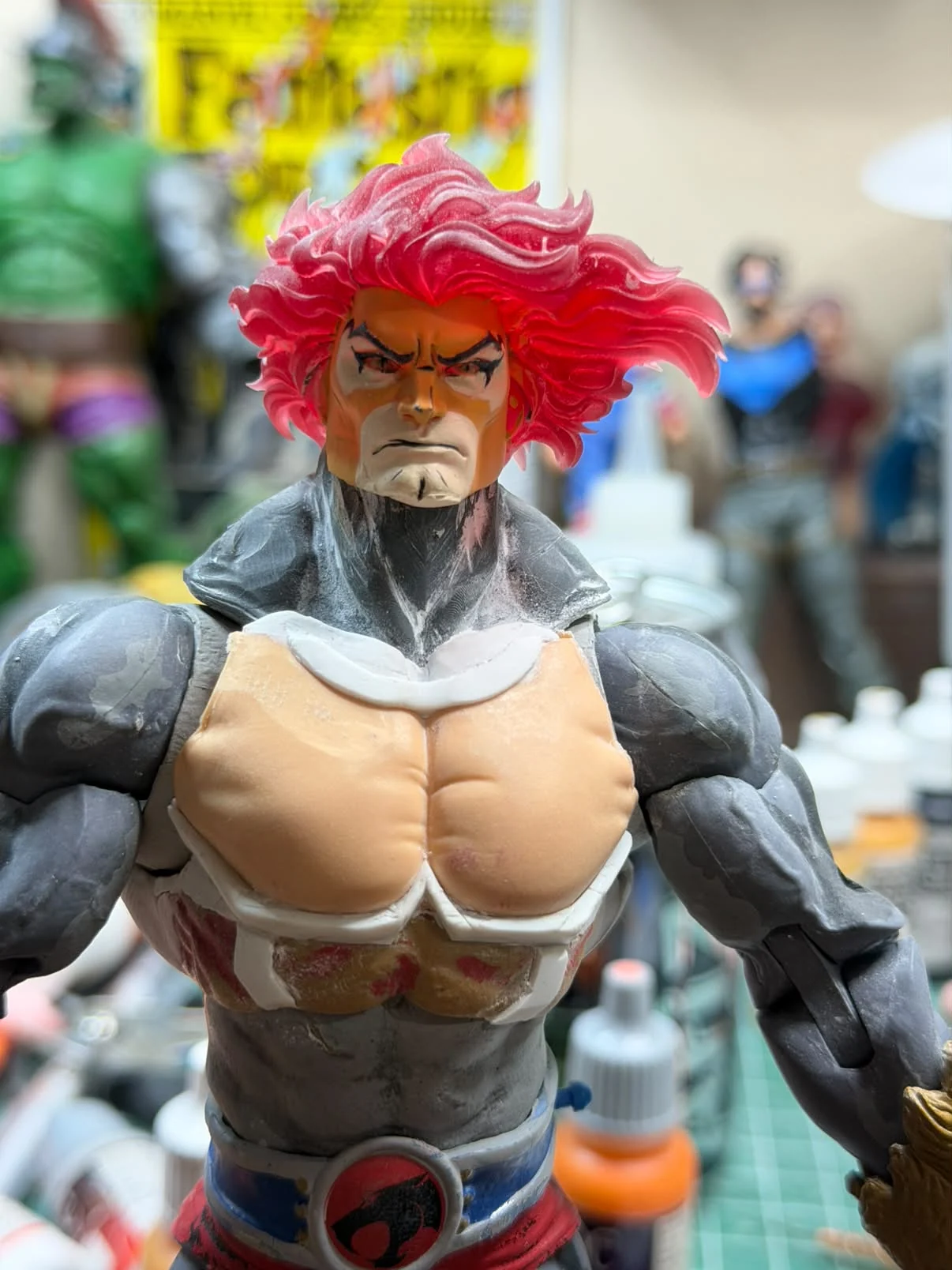 Close view of the painted Lion-O head and chest, red swept-back mane, black eye markings, blue and white chest armour over unpainted grey arms