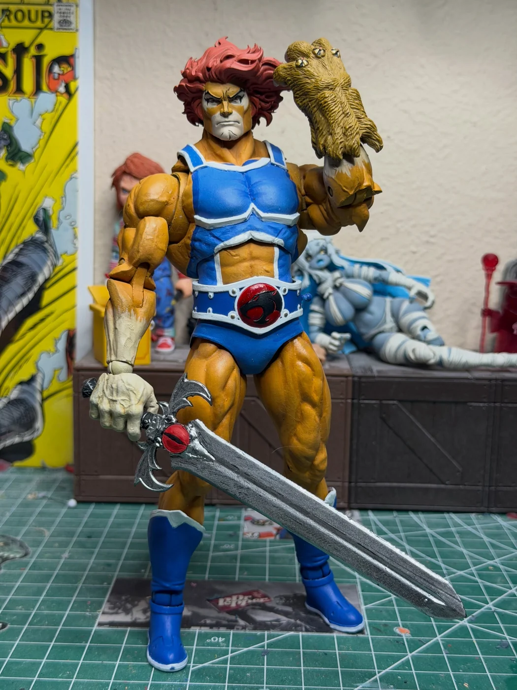 Finished custom Lion-O standing with the Sword of Omens held low in the right hand and the claw shield raised beside the head, blue and white armour over an orange body, red mane swept back