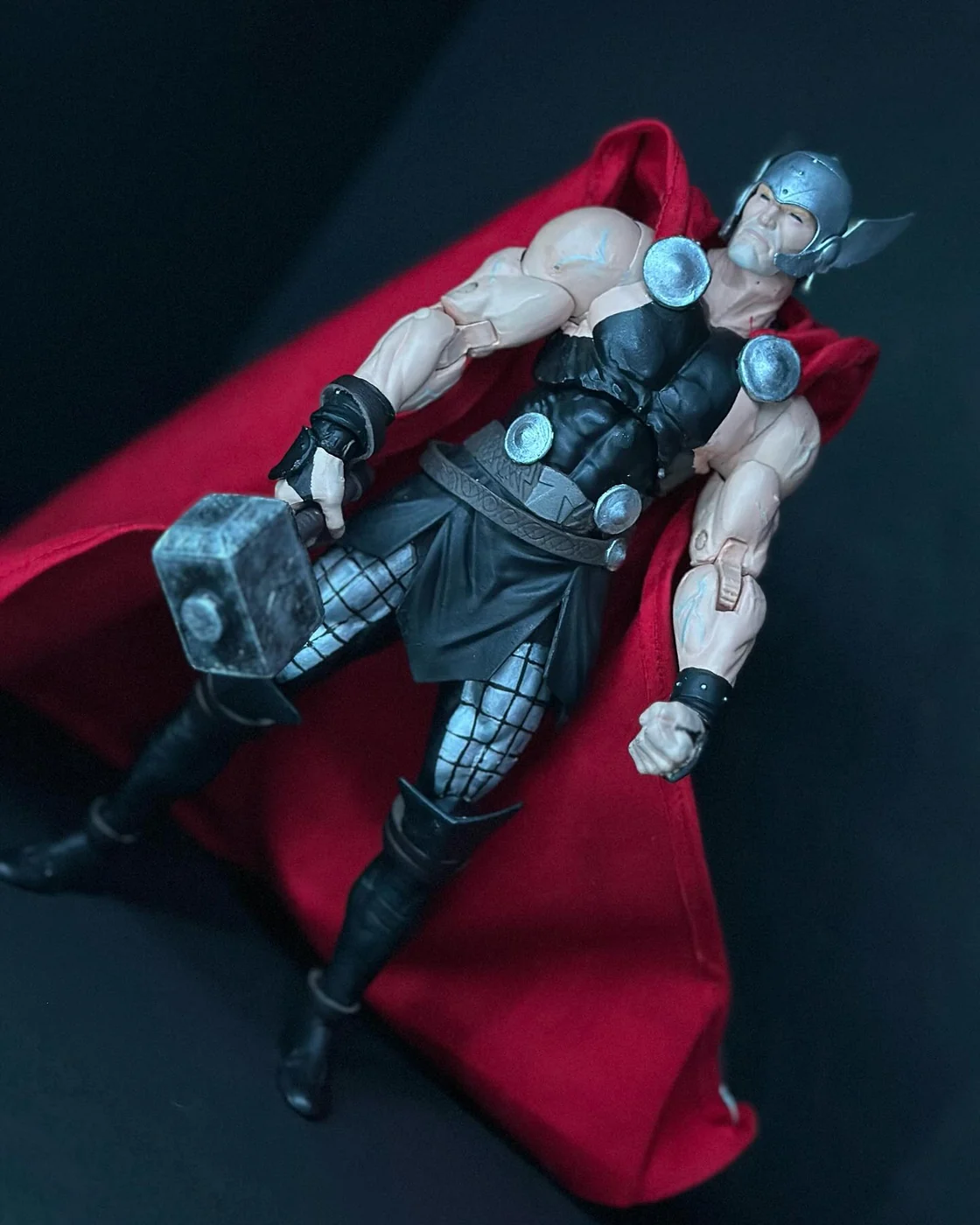 The same custom Thor figure posed on a spread red cape, holding Mjolnir low in one hand, chainmail leggings and a runed belt visible