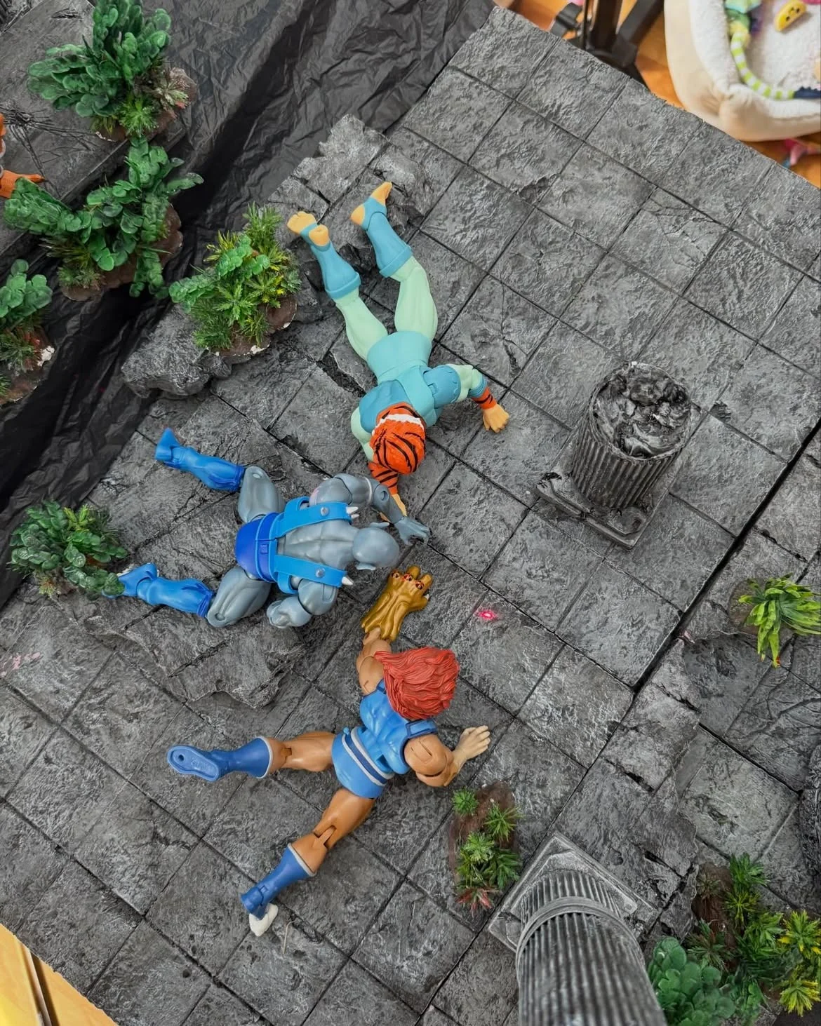 Overhead view of the Lion-O, Panthro and Tygra figures posed lying on the stone floor of the set before the effects were added