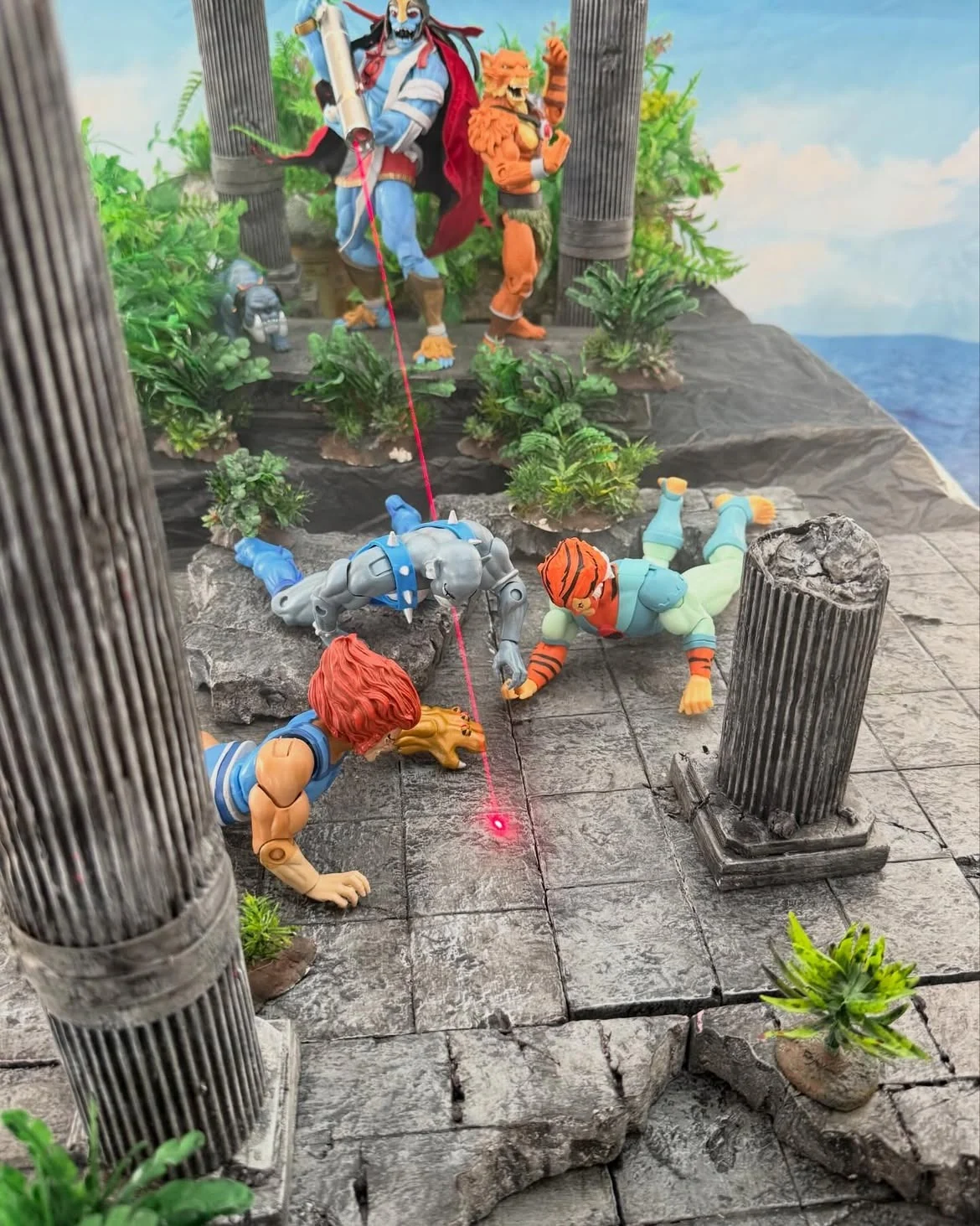 Overhead view of the diorama with the red laser beam running from the temple steps down to a bright dot on the stone floor