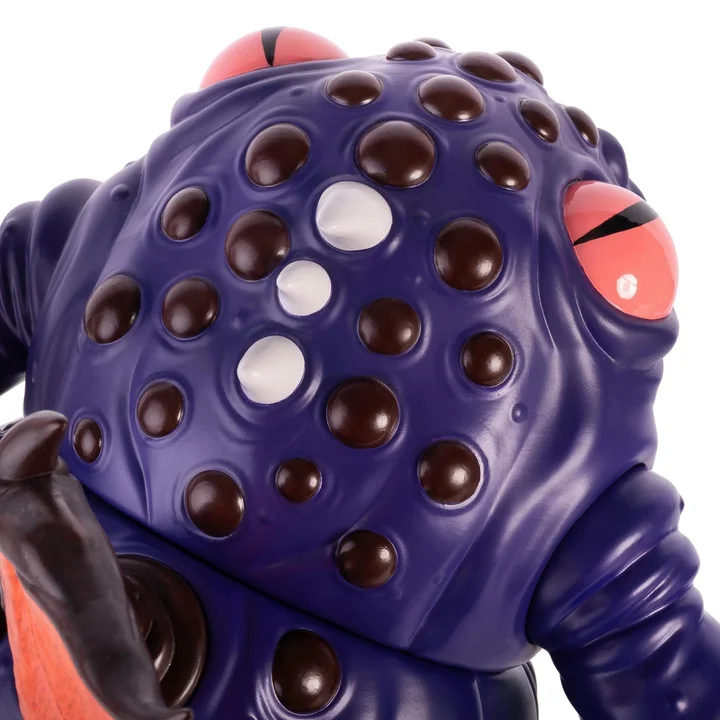 Close view of the Astral Moat Monster's domed crown, showing rows of dark brown studs with three pale ones among them and one slit pink eye at the right edge