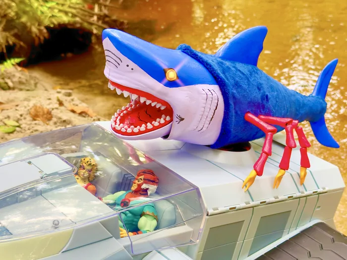 The custom Black Widow Shark clawing across the roof of a ThunderTank at the water's edge with two figures in the cockpit